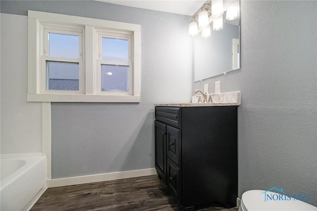 bathroom with hardwood / wood-style flooring, vanity, toilet, and a tub