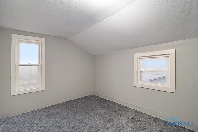 bonus room with a textured ceiling, dark carpet, plenty of natural light, and lofted ceiling