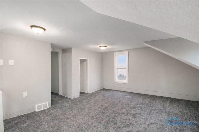 additional living space featuring vaulted ceiling and dark colored carpet