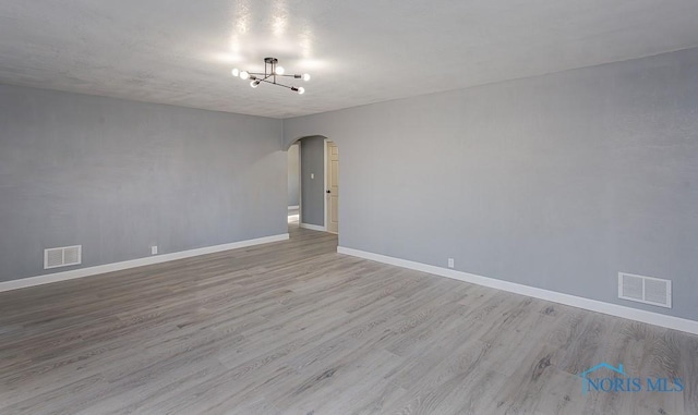 empty room with light hardwood / wood-style floors and a notable chandelier