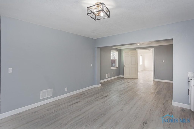 unfurnished room with light wood-type flooring and a chandelier