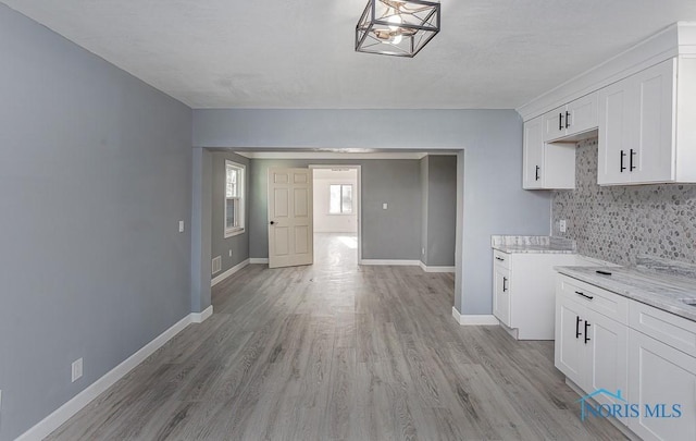 kitchen with decorative backsplash, light stone countertops, light wood-type flooring, decorative light fixtures, and white cabinetry