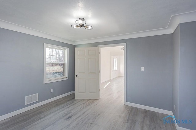 unfurnished room with crown molding and light wood-type flooring