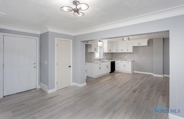 kitchen with white cabinetry, sink, black dishwasher, tasteful backsplash, and light hardwood / wood-style floors