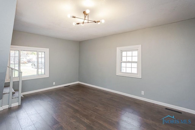 empty room featuring dark hardwood / wood-style flooring and an inviting chandelier