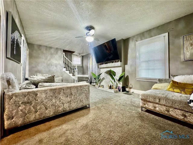 living room featuring carpet, a brick fireplace, ceiling fan, a textured ceiling, and plenty of natural light