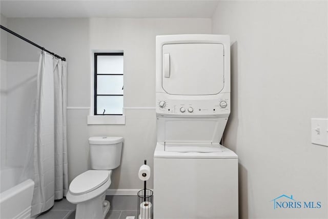 bathroom with tile patterned floors, shower / bathtub combination with curtain, stacked washer / dryer, tile walls, and toilet