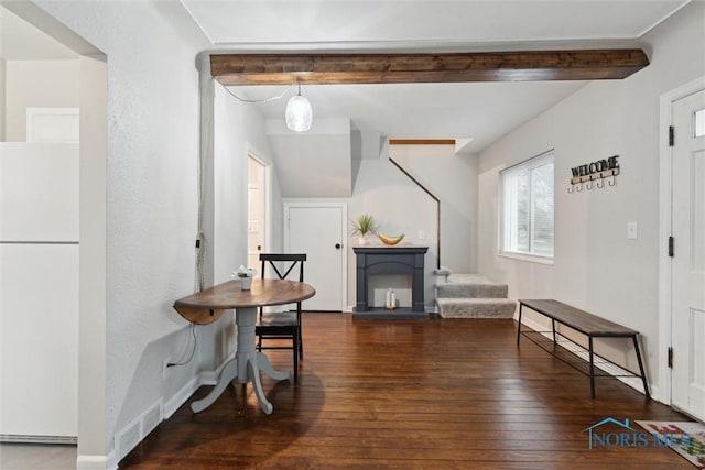 dining room with beam ceiling and dark hardwood / wood-style flooring