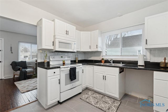 kitchen with light tile patterned floors, white appliances, white cabinetry, and sink