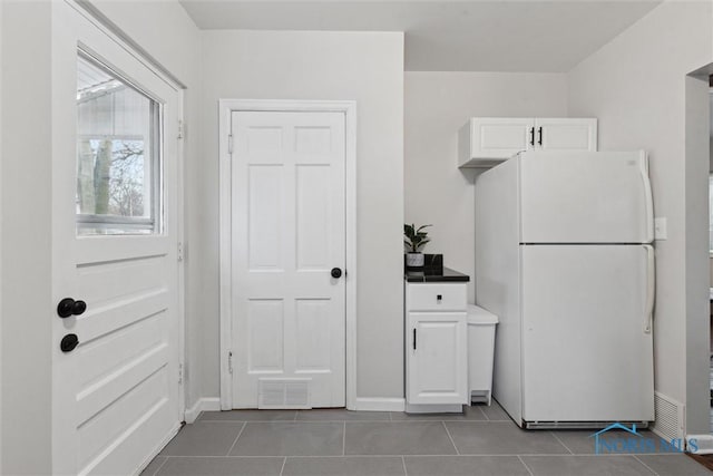 kitchen with tile patterned floors, white cabinets, and white fridge