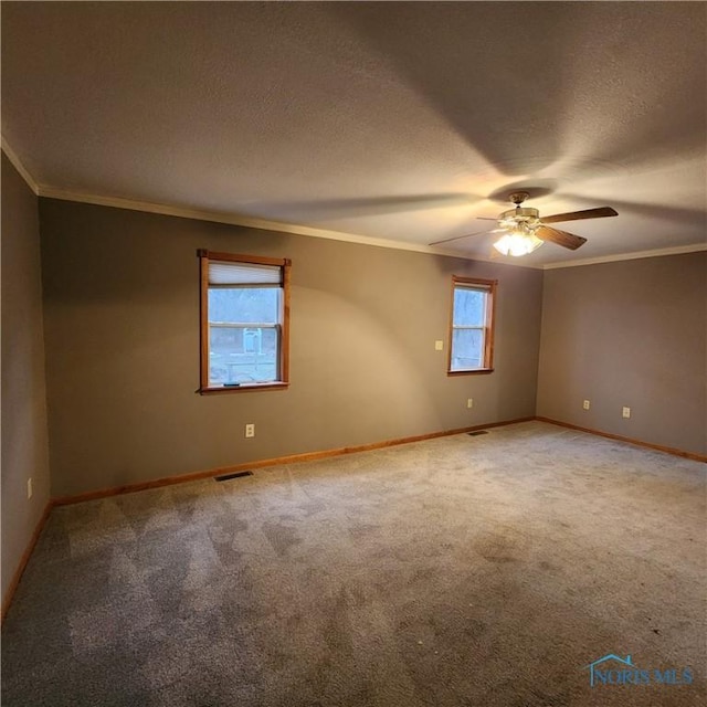 carpeted empty room featuring a textured ceiling, ceiling fan, and crown molding