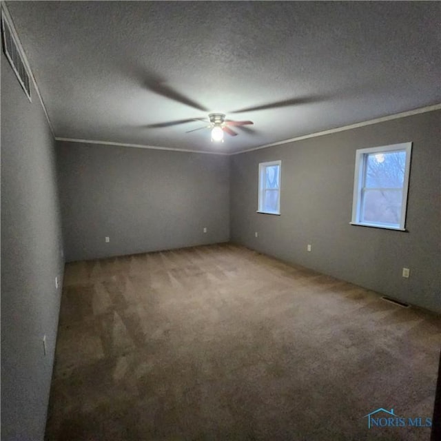 carpeted empty room featuring a textured ceiling, ceiling fan, and ornamental molding