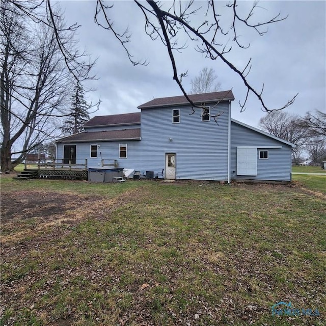 back of property featuring a deck and a lawn