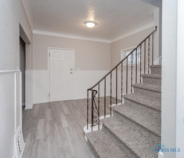 entryway with crown molding and light wood-type flooring