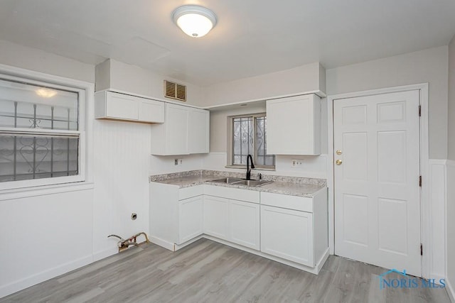 kitchen featuring light wood-type flooring, white cabinetry, and sink