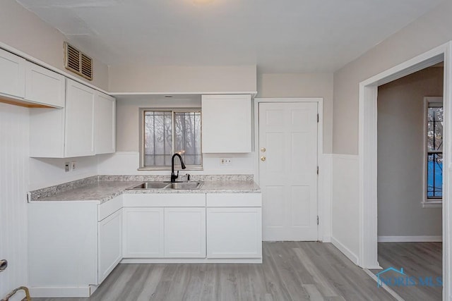 kitchen with sink, white cabinets, and light hardwood / wood-style floors