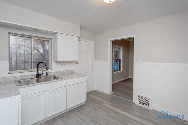 kitchen featuring white cabinets, sink, and light hardwood / wood-style flooring