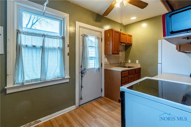 kitchen with ceiling fan, sink, light hardwood / wood-style floors, white appliances, and decorative backsplash