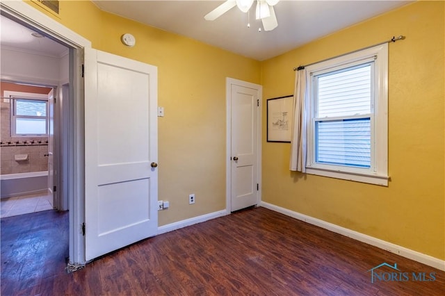 unfurnished bedroom with multiple windows, ceiling fan, dark hardwood / wood-style flooring, and ensuite bathroom