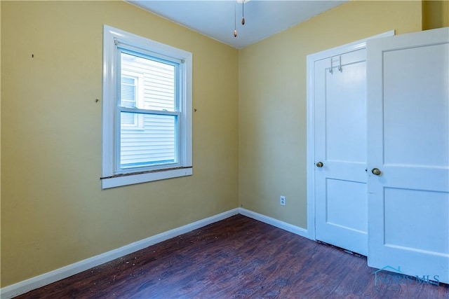 unfurnished bedroom with a closet and dark hardwood / wood-style flooring