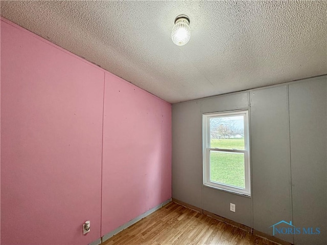 spare room featuring light hardwood / wood-style flooring and a textured ceiling