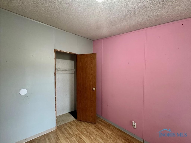 unfurnished bedroom with light hardwood / wood-style floors and a textured ceiling