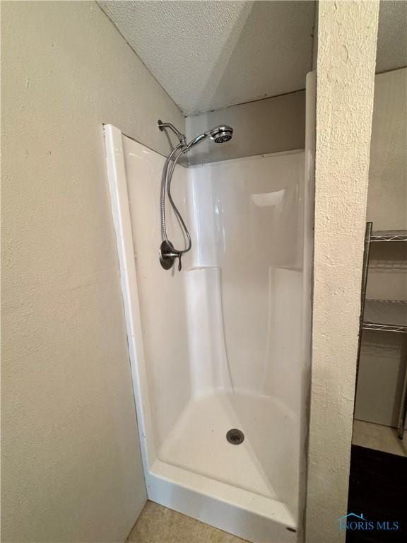 bathroom featuring a textured ceiling, tile patterned flooring, and walk in shower