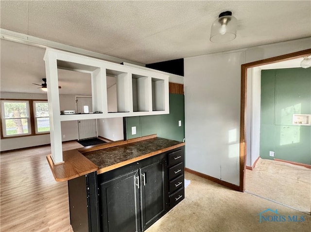 kitchen with a kitchen bar, a textured ceiling, and ceiling fan