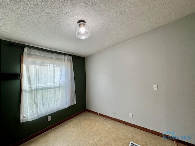 carpeted spare room featuring a textured ceiling