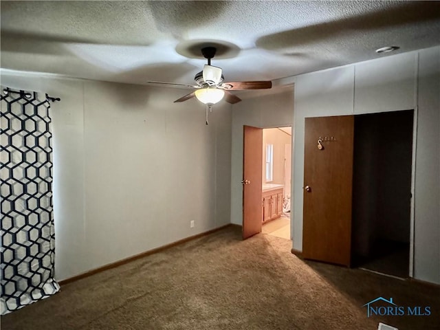 unfurnished bedroom featuring ceiling fan, carpet floors, a textured ceiling, and connected bathroom