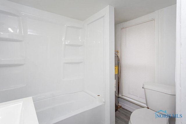 bathroom with hardwood / wood-style floors, toilet, and shower / washtub combination