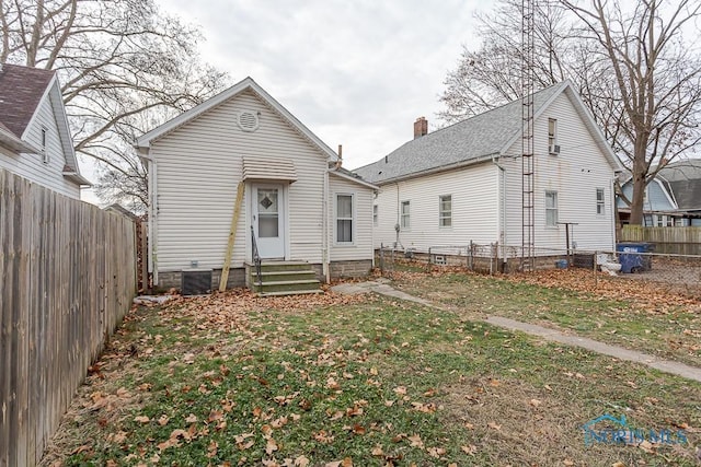 rear view of property with a yard and central AC unit