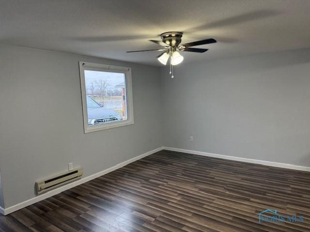 empty room with dark hardwood / wood-style floors, baseboard heating, and ceiling fan