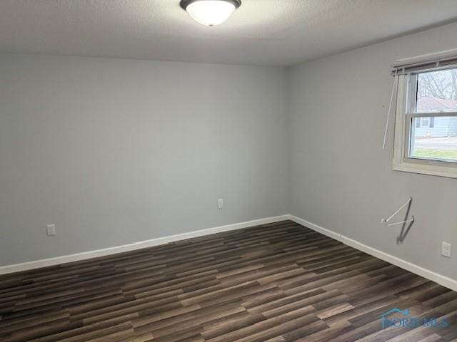 unfurnished room with a textured ceiling and dark wood-type flooring