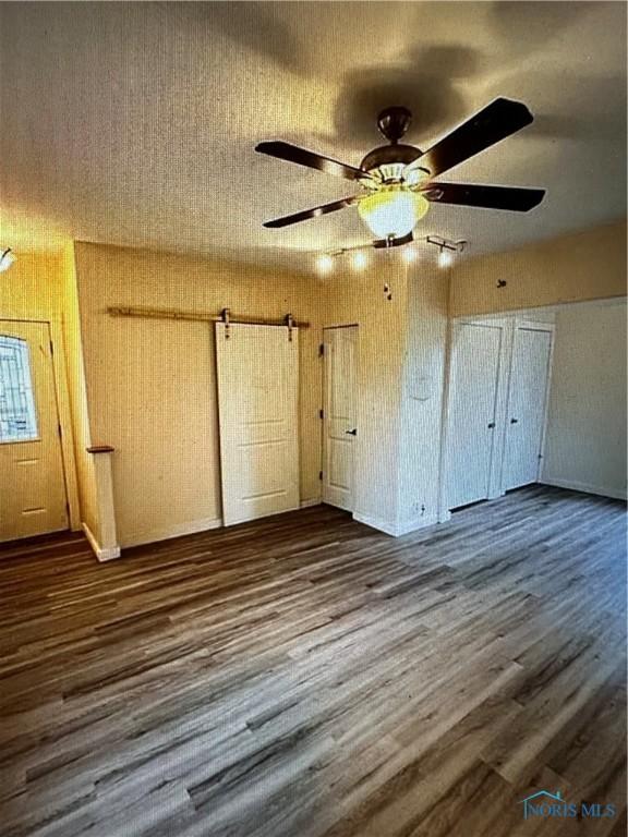 unfurnished bedroom with ceiling fan and dark wood-type flooring