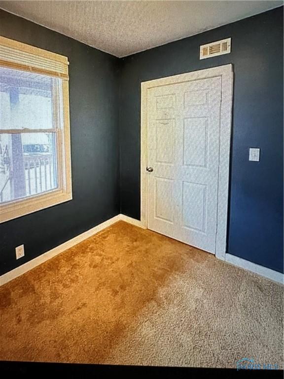 unfurnished bedroom with carpet and a textured ceiling