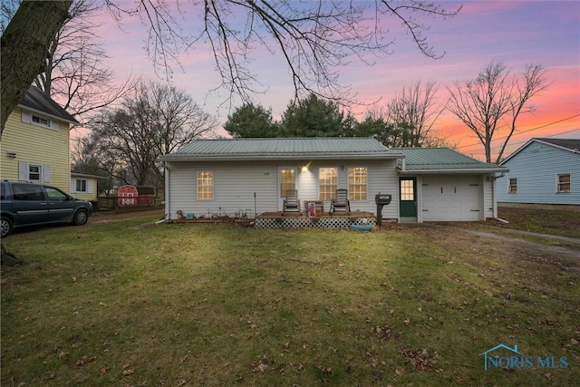 view of front of house with a lawn, a garage, driveway, and metal roof