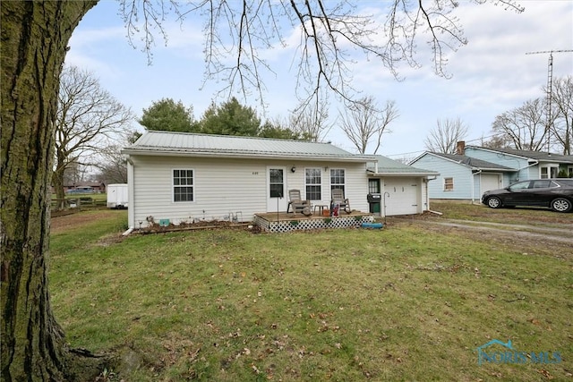 rear view of property featuring a yard, metal roof, a garage, and dirt driveway