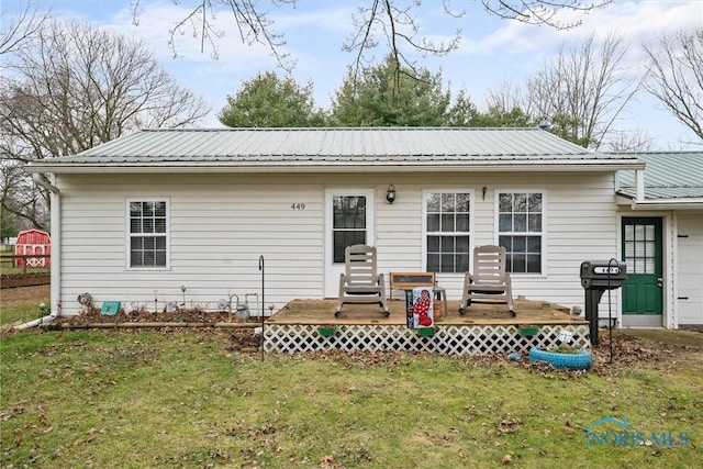 rear view of house with a deck, a lawn, a garage, and metal roof