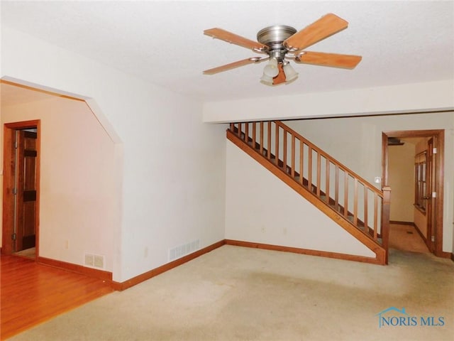 unfurnished living room featuring ceiling fan and light colored carpet