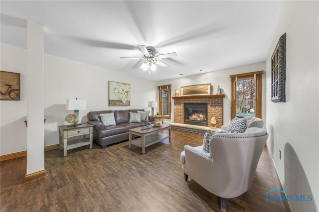 living room featuring ceiling fan, dark hardwood / wood-style flooring, and a fireplace