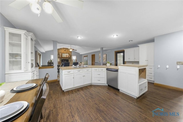 kitchen featuring white cabinetry, dishwasher, a stone fireplace, dark hardwood / wood-style floors, and lofted ceiling