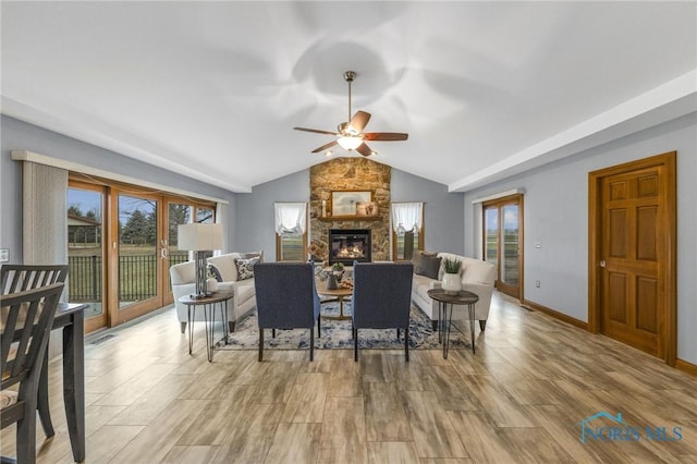 living room featuring vaulted ceiling, a stone fireplace, and ceiling fan