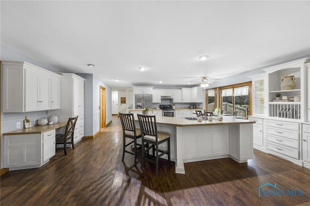 kitchen featuring white cabinetry, ceiling fan, stainless steel appliances, dark hardwood / wood-style floors, and a kitchen island with sink