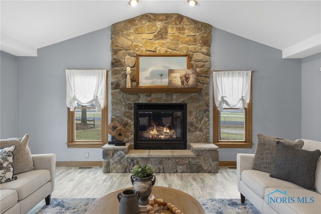 living room featuring a stone fireplace, wood-type flooring, and lofted ceiling