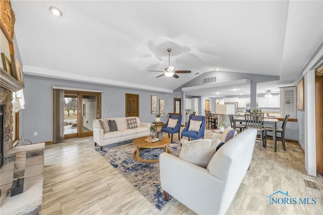 living room featuring a large fireplace, vaulted ceiling, and ceiling fan