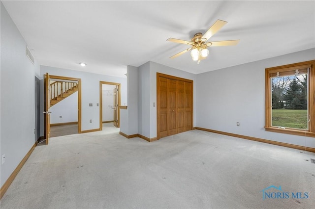 unfurnished bedroom featuring ceiling fan, a closet, and light carpet