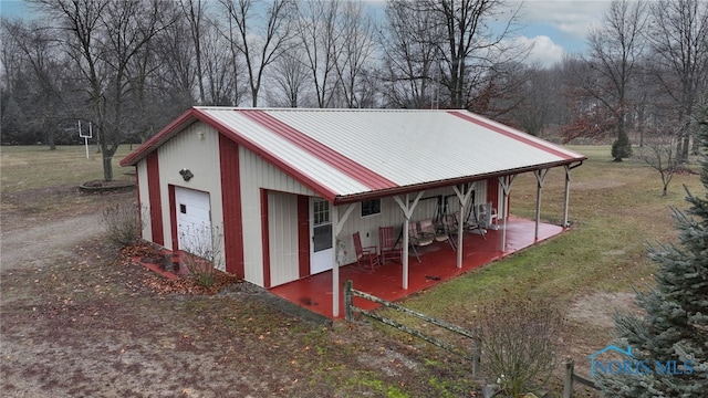 view of outdoor structure with a porch, a garage, and a yard