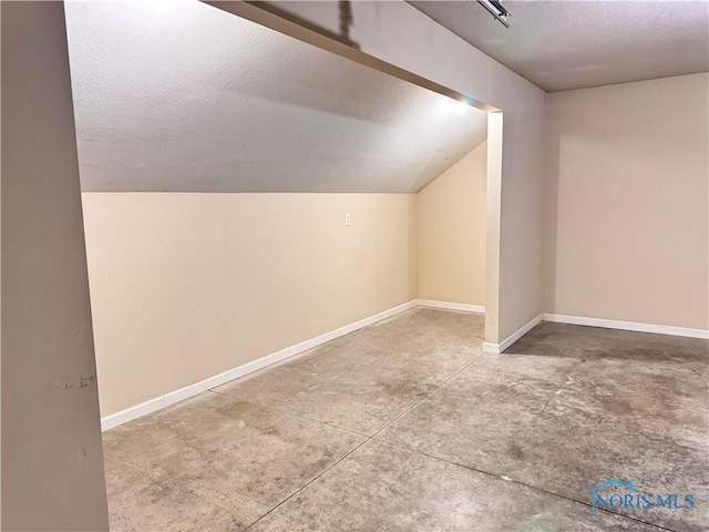 bonus room with concrete flooring, a textured ceiling, and vaulted ceiling