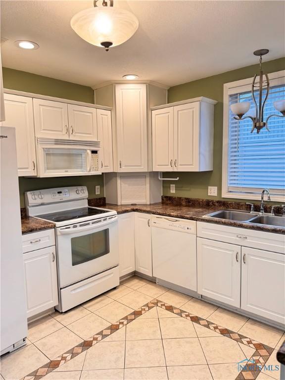 kitchen with white appliances, sink, light tile patterned floors, white cabinets, and hanging light fixtures